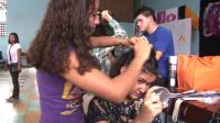 Mujer jóven le corta el cabello a otra mujer 