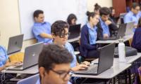 Estudiantes trabajan en una clase con sus computadoras portátiles