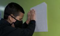 Estudiante con mascarilla leyendo braille