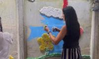 señora pegando tapitas en la pared del mural
