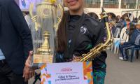 Aparece joven con un trofeo y certificado.