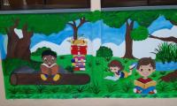 Mural en pared de niños y niñas leyendo debajo de un árbol