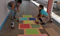 Dos mujeres pintan un juego de rayuela en el piso